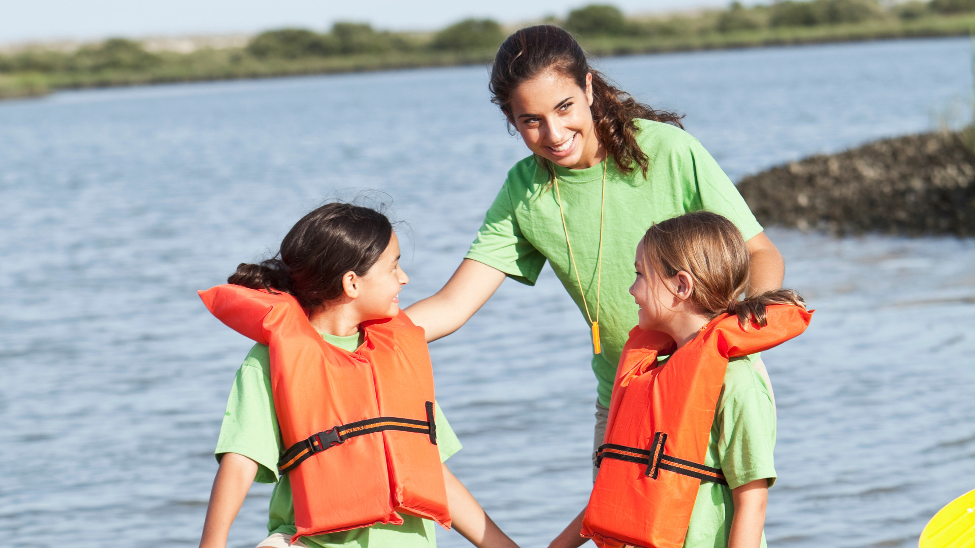 Monitora con dos niñas con salvavidas en una actividad en un río